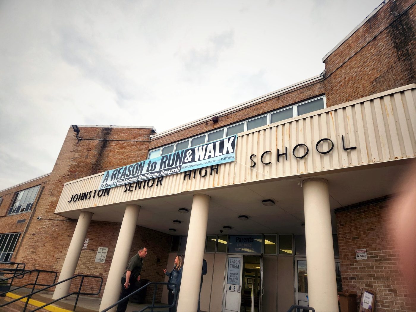 The Reason to Run banner hanging over the main entrance of Johnston Senior High School on event day
